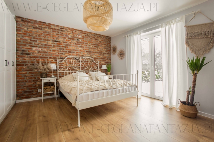 Przytulna sypialnia z ceglaną ścianą z cegły rozbiórkowej.