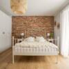Sypialnia w stylu glamour z białym łóżkiem, białymi meblami i ścianą z cegły