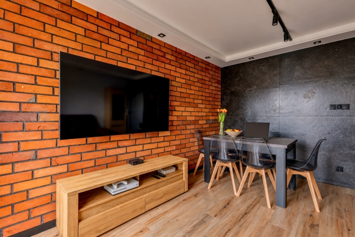 Home office z cegłą rozbiórkową na ścianie i laptopem na biurku