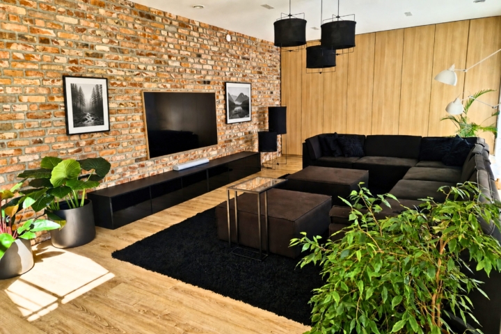 Nowoczesny salon z cegłą rozbiórkową na ścianach i drewnianymi dodatkami
